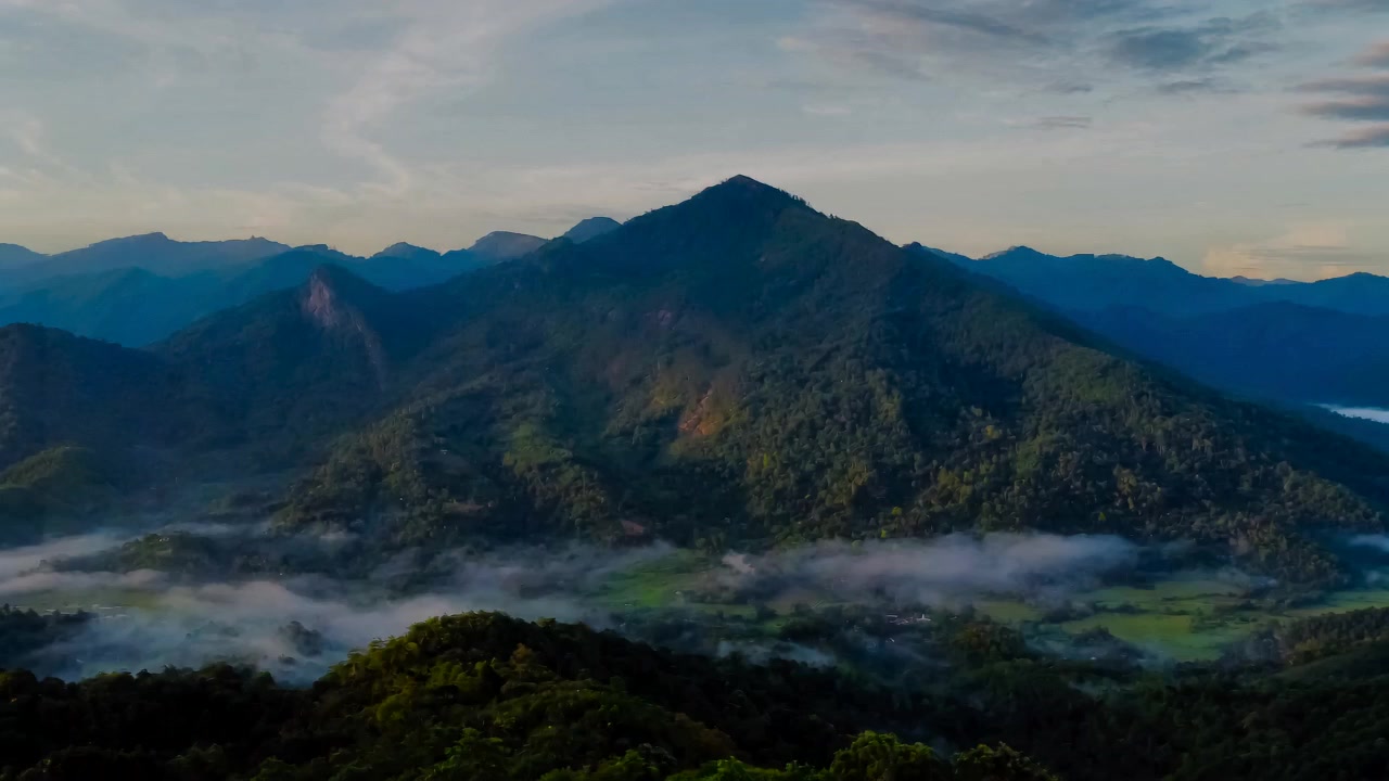 Forested mountains and mist across a green valley.